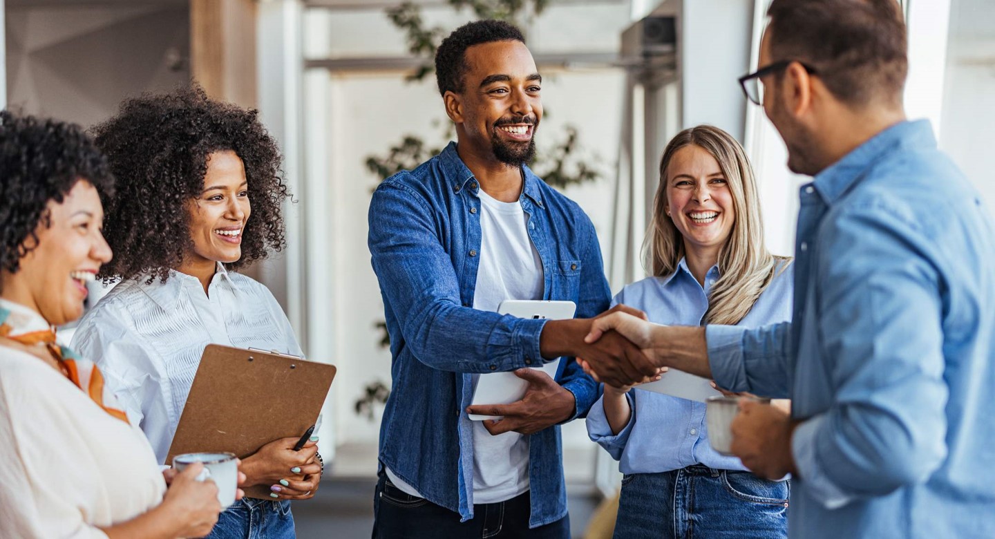 A group of individuals shaking hands with each other in a meeting.