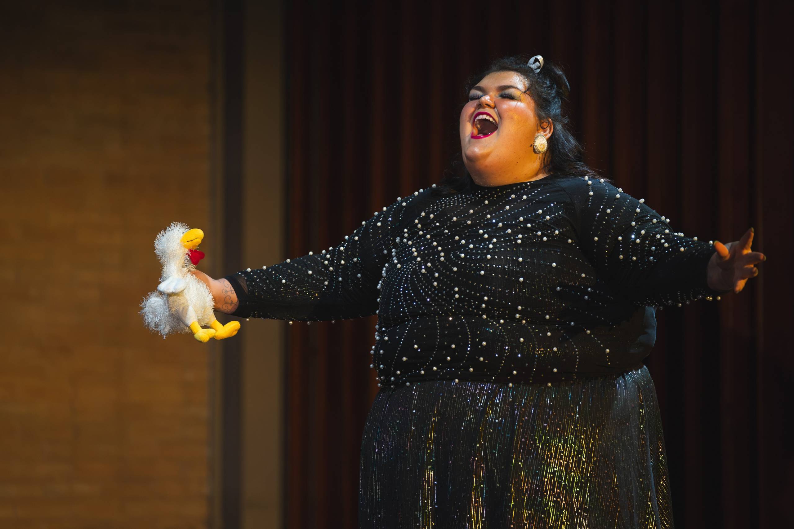 Emma Pennell holding a puppet and performing on stage.