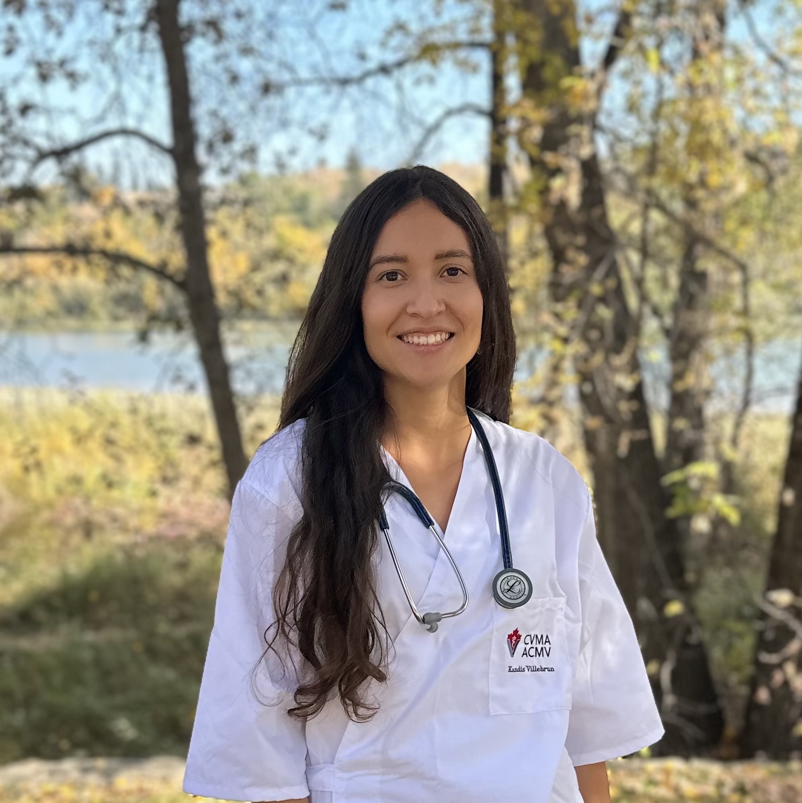 Kandis Villebrun wearing a stethoscope and standing outside in nature. 